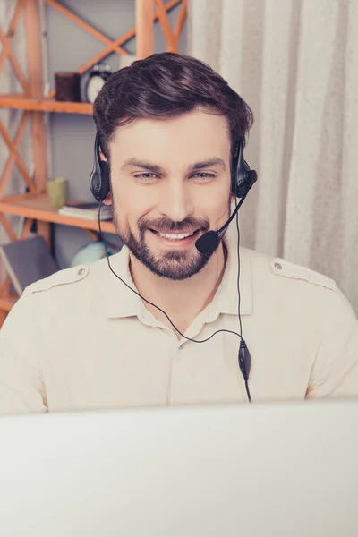 Close up portrait of cheerful young worker in head-phones talkin