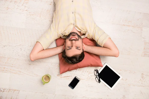 Top view photo of man lying on the floor with cup, phone, glasse