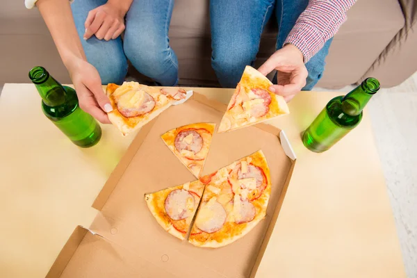 Top view photo of man and woman eating pizza with beer