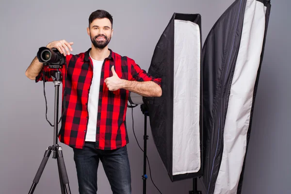 Handsome photographer with camera in photo studio gesturing 