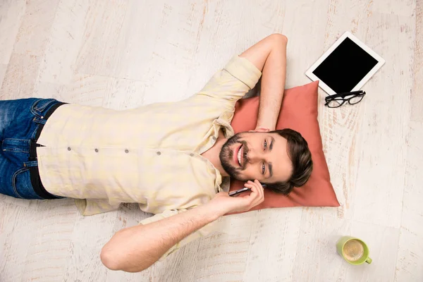 Top view photo of man lying on the floor and talking on phone