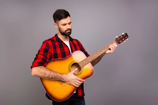 Young handsome musician holding guitar and playing