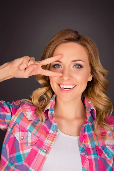 Cheerful happy young woman holding  two fingers near eyes