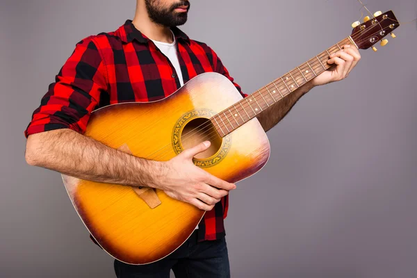 Close up portrait of young bearded man holding guitar
