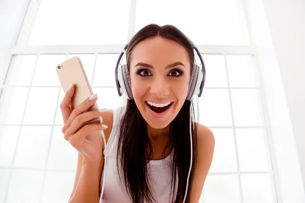 Happy crazy girl listening to music with  white headphones and s