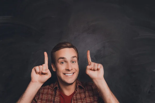 Portrait of cheerful young man pointing up with fingers