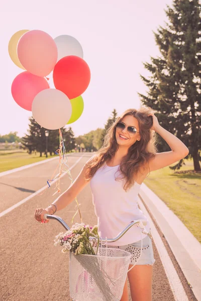 Portrait of pretty happy woman in glasses with bicycle and ballo