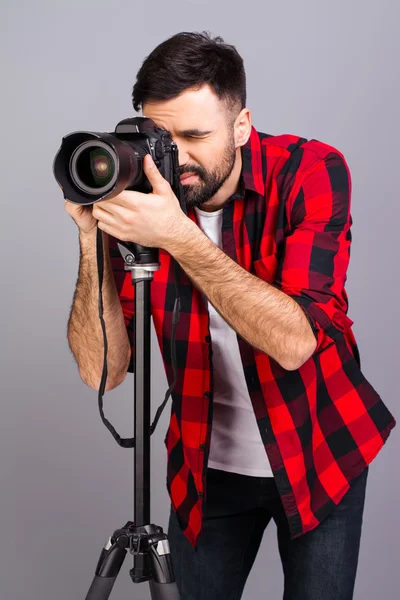 Portrait of young successful photographer taking photos in studi