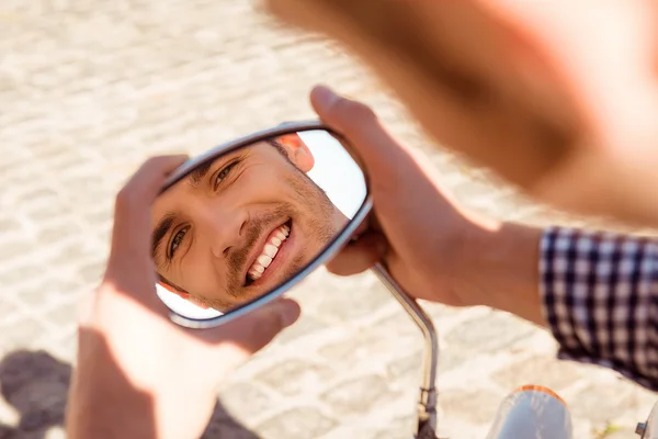 Reflection of a young handsome man in the mirror of bike