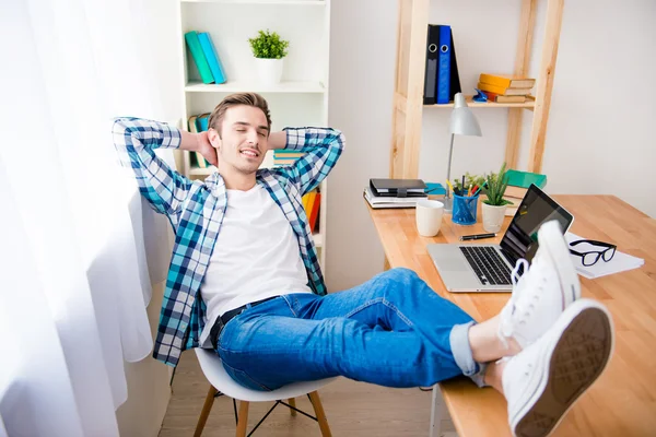 Relaxed happy man  dreaming and holding legs on table
