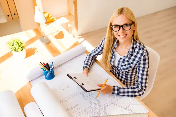 Top view of smiling woman in glasses working on scheme