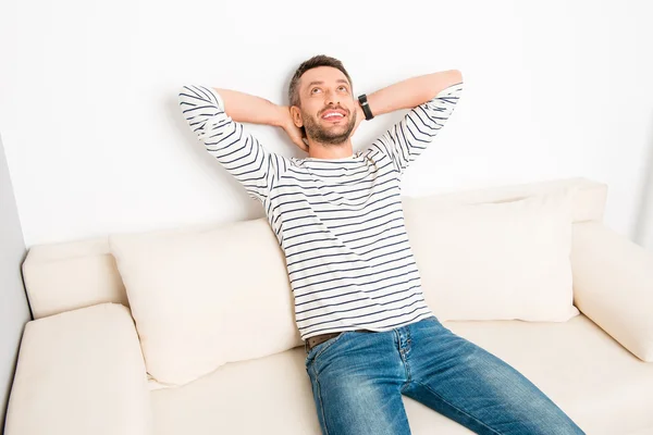 Happy young man sitting on sofa and resting after long day
