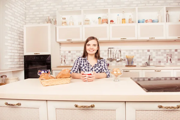 Portrait of smiling woman drinking coffee with baked cakes