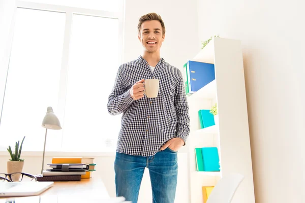 Cheerful happy man completed job and drinking coffee