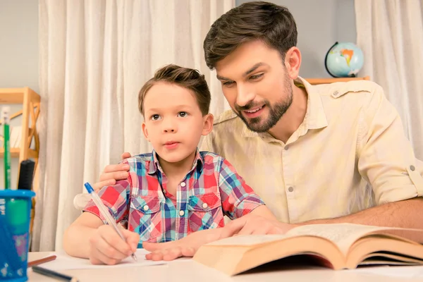 Young father teaching little son how to write