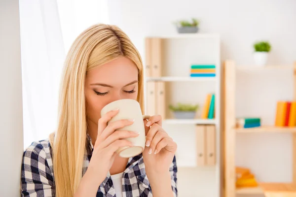 Portrait of young woman resting and drinking coffee in office