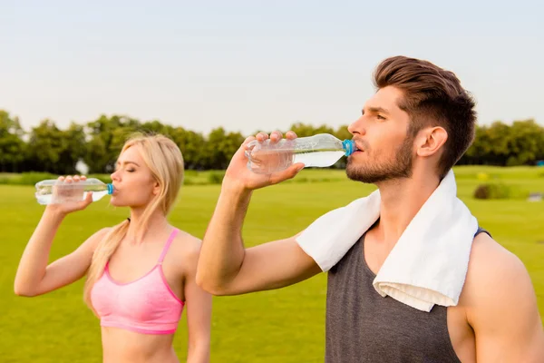 Fit healthy man and woman drinking water after exercise