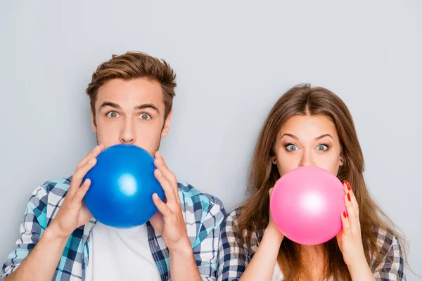 Portrait of happy young  man and woman inflating balloons