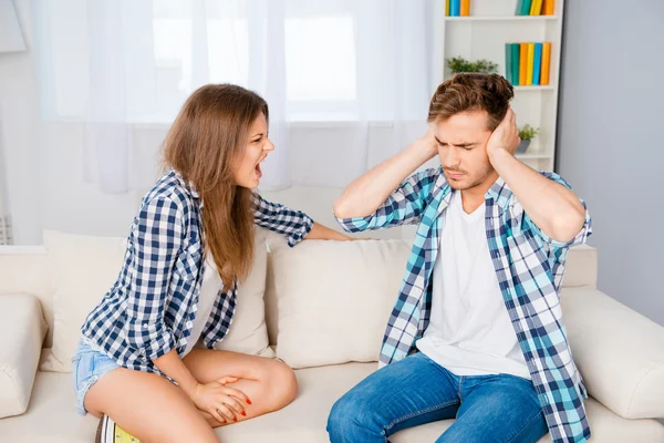 Problems in the family. Man covering ears while his wife screami