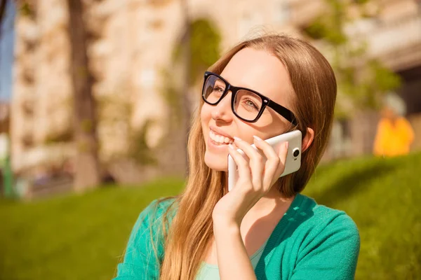 Portrait of happy woman in glasses talking on phone in park