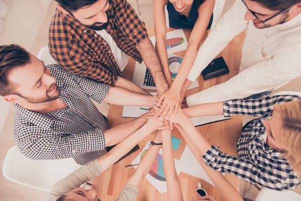 Top-view of many hands clasped together . People strong when the