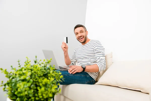 Happy man doing internet shopping and holding credit card