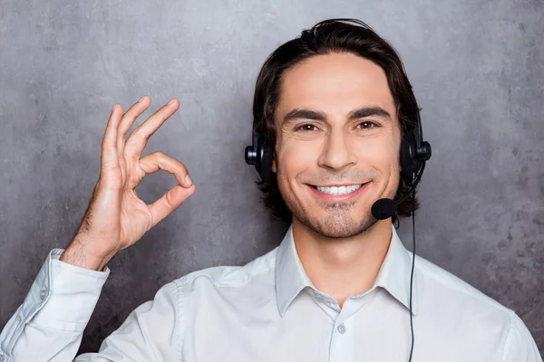 Handsome young operator in call-center with headphones showing o
