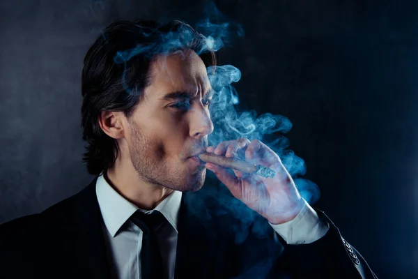 Portrait of brutal handsome man with stubble smoking a cigar