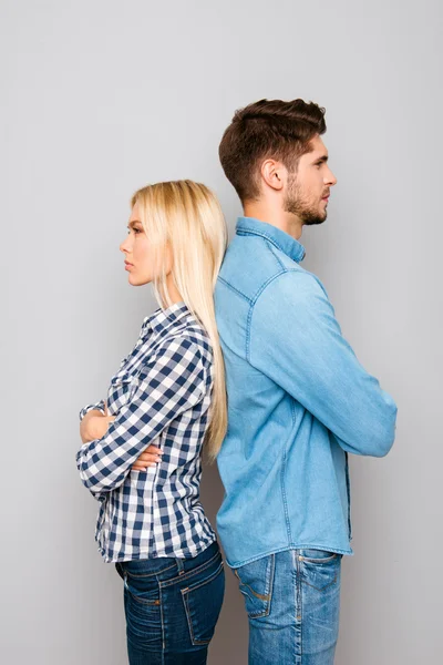 Serious man and woman with crossed hands standing back to back