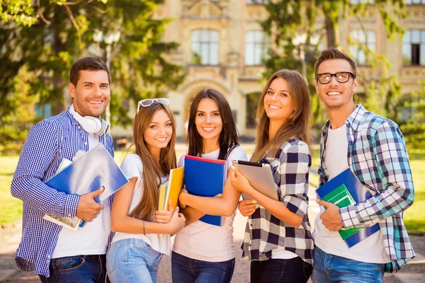 Happy attractive diverse five students standing near university