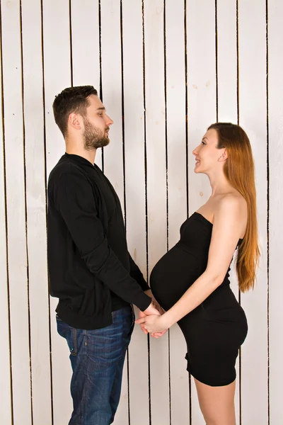 Man holding hands his pregnant girl. Young future parents holding hands and looking at each other. couple in love in an elegant black clothes