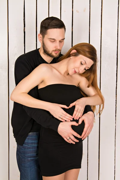 2 hearts formed with hands on the belly of a pregnant woman with twins. handsome man with his beautiful pregnant woman. man and woman looking at a big tummy