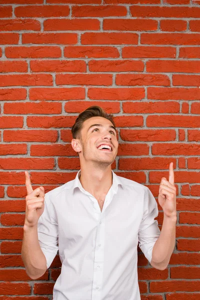 Happy young man pointing up and smiling