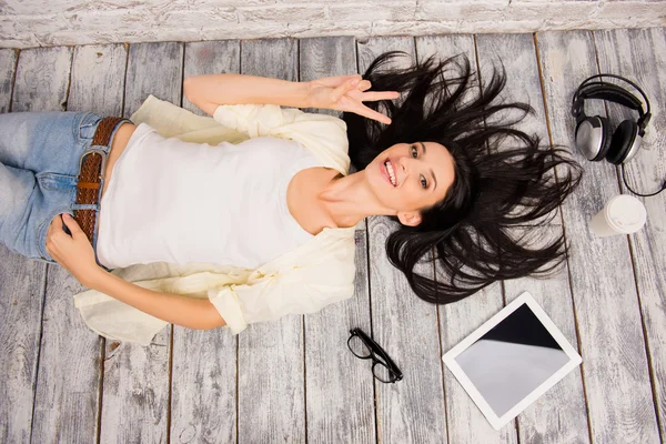 Top view of pretty girl lying on the floor with tablet, headphon