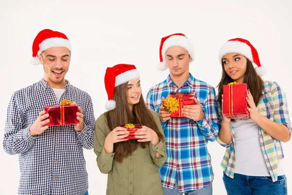 Young cheerful people in santa hats holding presents