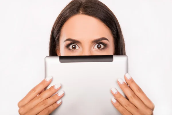 Frightened young woman hiding face behind the tablet