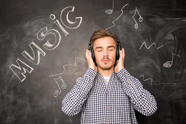 A young man listens to music in headphones