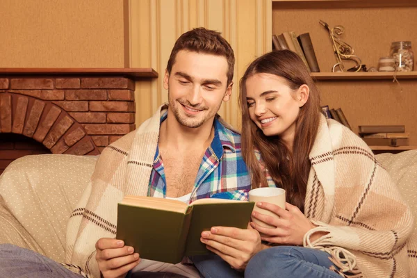 Young cute couple reading together under the plaid