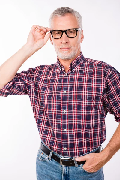 Confident gray aged man with glasses keeping his hands in pocket