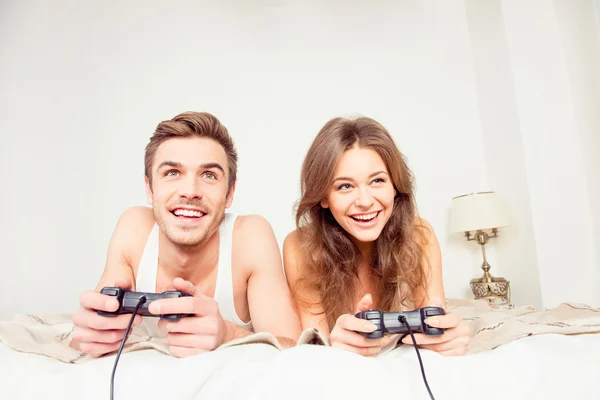 Happy couple in love playing video games with joysticks on the b