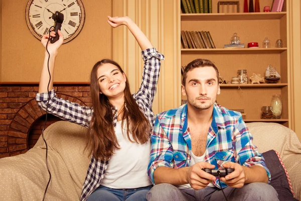 Happy couple in love at home playing games joysticks, she wining