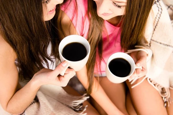 Two girls with cups of coffee in hands,  close up photo