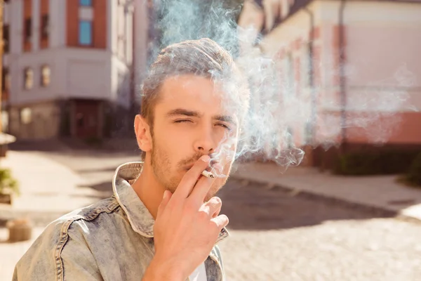 Close up portrait of handsome man smoking cigarette