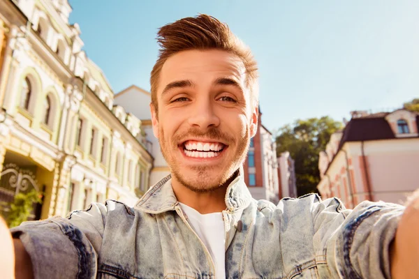 Cheerful happy man making comic selfie on the street