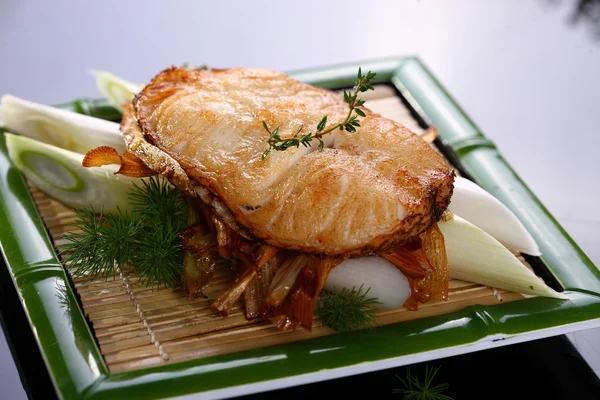 Fried loin of cod with onion on bamboo tray in restaurant