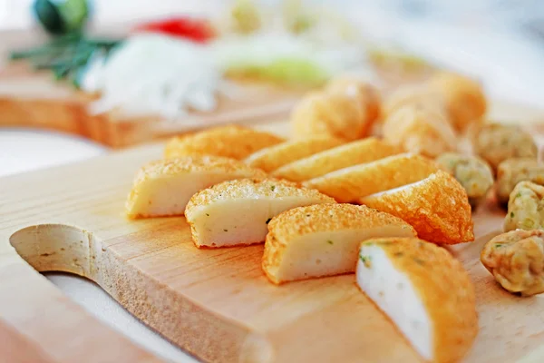 Sliced fish cake laksa on wooden cutting board in kitchen