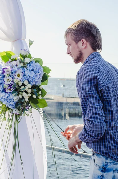 Professional florist at work: young handsome male making fashion modern composition bouquet of blue and white different flowers. Floral Design. Job concept serious bearded man working outdoors summer