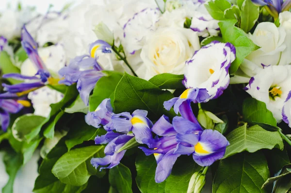 Beautiful blue iris flower with lush leaves, white hydrangea, delicate cream roses. Summer wedding concept background. Floral arrangement, design. The bride and groom ceremony.