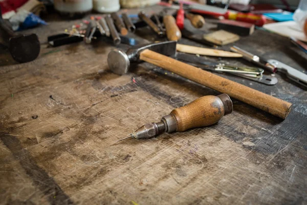 Leather crafting tools on working desk with the scratches