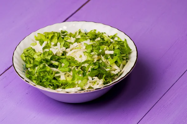 Cabbage salad in a plate on a wooden table.
